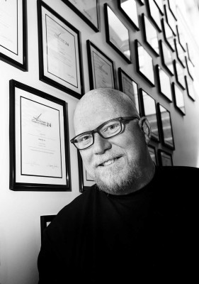 Thomas Roskelly in the office stairway surrounded by some of the many awards.